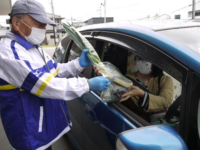 車の運転席から野菜を受け取る市民