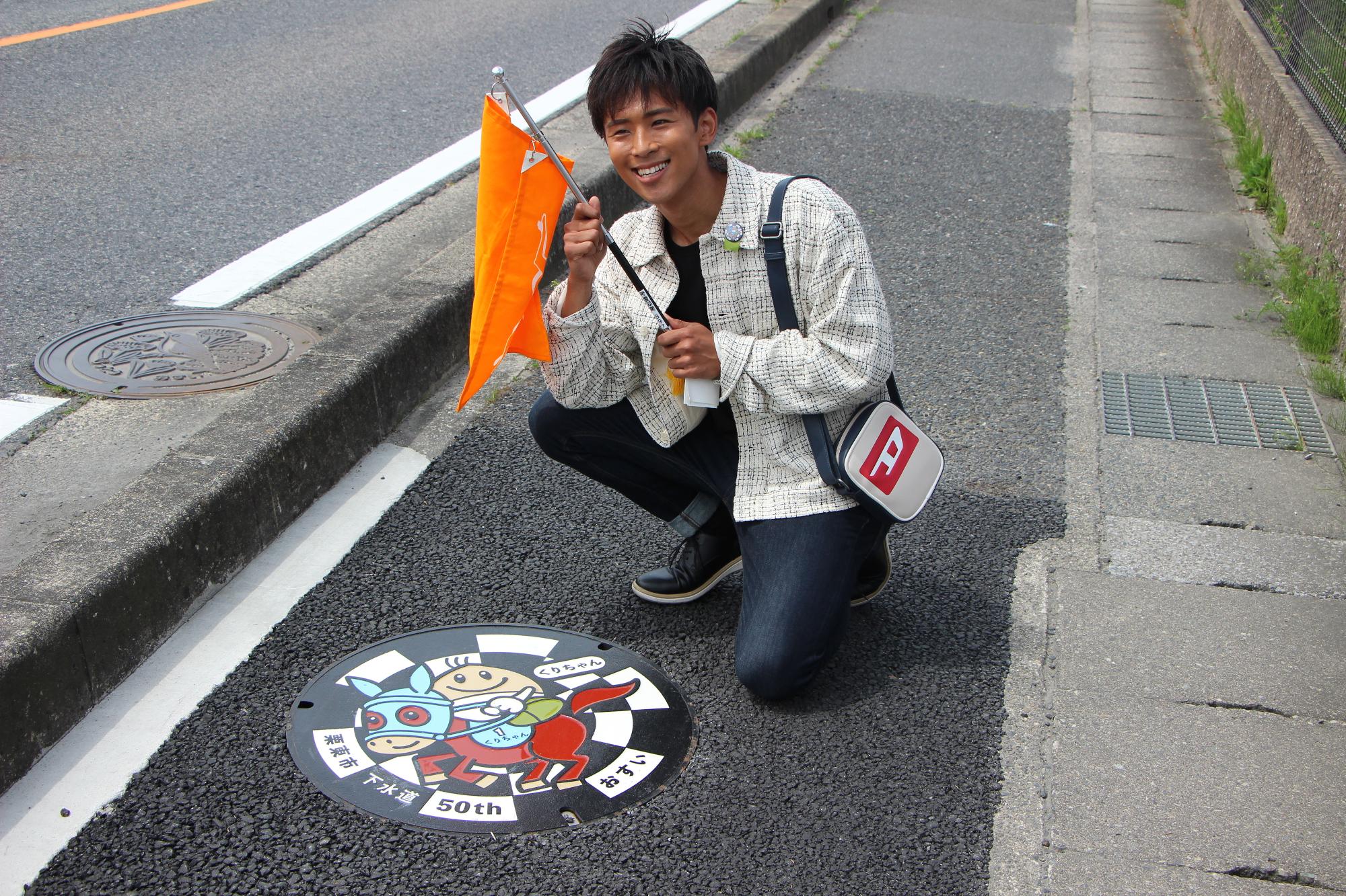 白上一成さんが田舎の元気や入口前通路のくりちゃんマンホールと記念撮影